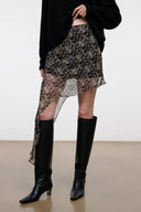 SEPHIE short skirt with speckled black-and-cream print, asymmetrical hem and draped overlay