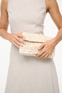 Cream woven shoulder bag held by model with hands resting on front