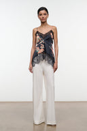 Noir floral silk camisole top with lace hem and adjustable straps, worn with white trousers