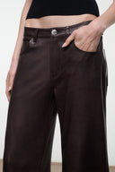 Dark brown leather pants close-up, button front, belt loops, and front pockets.