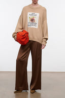 Beige knit sweater with crew neck and centered front graphic, dropped shoulders