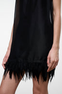 Black sleeveless mini dress close-up with feather fringe hem