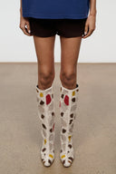 Feet shot of tall suede patchwork boots, cream with multicolor heart pattern and block heel