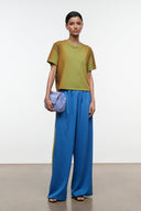 Blue wide-leg pants with elastic waistband and yellow side stripe, flowing drape