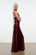 Wine satin halter maxi dress with diagonal halter strap and flowing skirt.