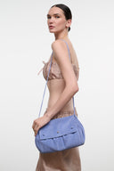Blue convertible shoulder bag with wide flap and gold-tone snap, worn crossbody