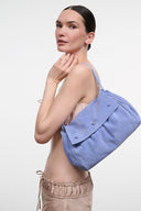 Blue convertible handbag with flap and gold-tone snap closure, side view with strap