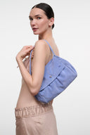 Blue convertible shoulder bag with flap and snap closure, held over shoulder