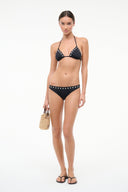 Black bikini bottom side view with metal-stud waistband trim, low-rise