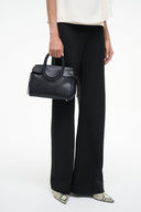 Black Maude mini carryall bag side view on model, zipper trim and top handle
