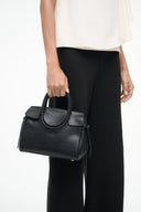 Black Maude mini carryall bag held by model, structured mini shape with top handle