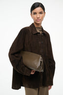 Truffle-brown soft clutch bag with top zipper, held at chest level