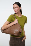 Brown leather satchel bag with top handles and zip closure, side view