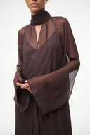 Brown long-sleeve maxi dress with high neck scarf detail and sheer sleeve overlay