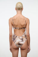 Back view of tan and brown cityscape printed one-piece swimsuit with thin straps and cutout back