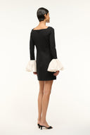 Black long-sleeve mini dress with ivory ruffled cuffs, back view