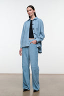 Sky blue suede pants on model, with button closure, belt loops, and wide leg fit.