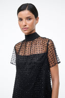 Mini dress close-up: mock neck with sheer star-pattern overlay over dark onyx fabric.