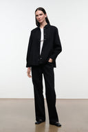 Black shirt jacket with stand collar and button front, long sleeves; front three-quarter view.