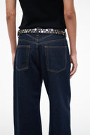 Black studded belt with silver moon buckle across dark blue jeans