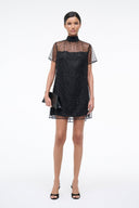 Mini shift dress in dark onyx with sparkly fabric, mock neck, sheer star-pattern sleeves.