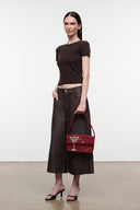 Red beaded handbag with top handle and front flap, carried at side by a model