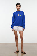 Blue crewneck knit sweater with beach-themed embroidered patch and lace trim shorts