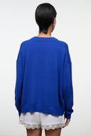 Back view of blue knit crewneck sweater with embroidered patch detail on rear