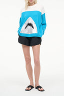 Turquoise crewneck sweater with white graphic of black jagged teeth, long sleeves