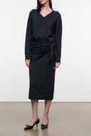 Dark knit sweater dress with V-neck, long sleeves, and waist-tie drape