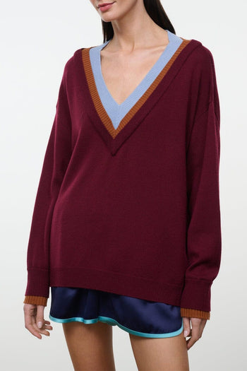 Women's maroon V-neck sweater with orange and blue striped neckline and ribbed cuffs