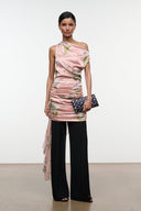 Pink silk dress with tapestry floral print, ruched one-shoulder top over black wide-leg pants