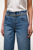 High-rise vintage wash denim jeans with crystal fringe belt, front button closure, and scoop pockets
