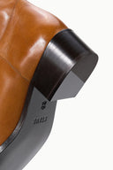 Cashew brown over-the-knee boot heel with black rubber sole and logo detail