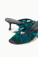 Black kitten-heel mule detail with teal feather trim and open side design