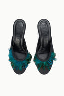 Black mule pair with teal feather trim, showing VELA logo on insoles