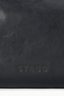 Black leather convertible bag close-up with embossed STAUD logo