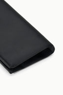 Black clutch bag corner close-up with folded edge and smooth lining