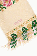 Close-up of beaded fabric with green dinosaur figures and colorful border fringe