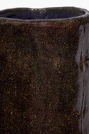 Close-up of dark speckled ceramic candle side with glazed textured speckle