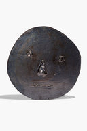 Ceramic face ornament in dark burnt black glaze, round with embossed facial features