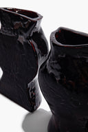 Black glossy ceramic vase bookends, close-up of curved side openings