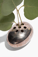 Vintage silver flower frog with oval base and perforated holes, surrounded by green leaves