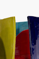 Ceramic bookends close-up with glossy yellow, dark blue, and red glazed arcs.