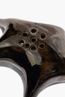 Ceramic ikebana holder close-up of 9 circular openings in metallic dark glaze