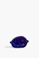 Small ceramic dog bowl, glossy blue with raised dog-face design, angled view