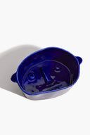 Small ceramic dog bowl, glossy blue with dog-face embossing and side rim