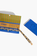 A Staud paper reed diffuser stick in its blue and yellow striped packaging, shown next to its blue cap on a clean white background.