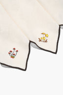 Natural embroidered napkins with black-trimmed edges and small corner motifs