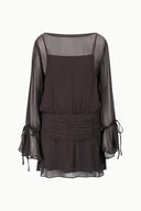 Back view of Earth-toned mini dress, sheer long sleeves, gathered waist, tie cuffs